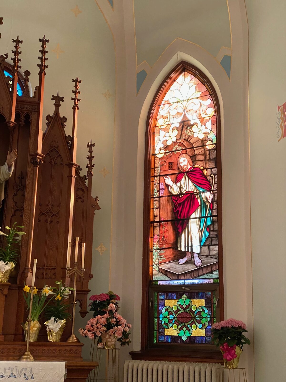 Christ stained-glass window above the altar with chalice and Easter flowers