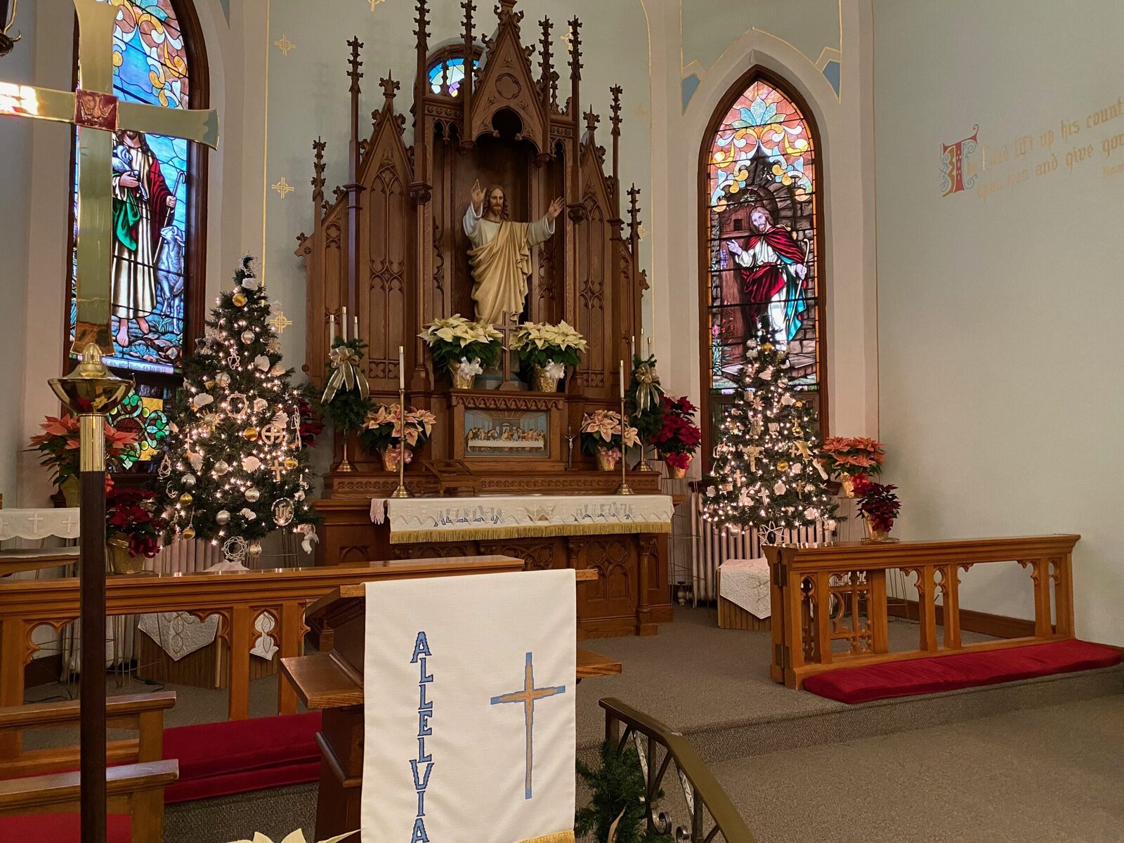 St. John sanctuary at Christmas — Alleluia banner and Christmas trees framing the altar