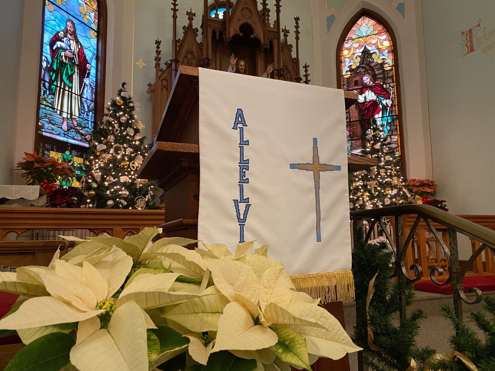 Alleluia banner above the altar at St. John, framed by Christmas poinsettias