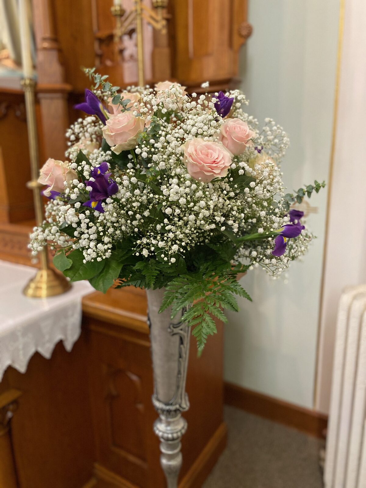 Wedding bouquet of roses, baby's breath, and iris on an altar stand at St. John